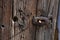 Old wooden door, closeup of door handle, closing mechanism. Rusted iron components and old creased wood surface