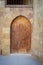 Old wooden door framed by arched bricks stone wall, Darb al Ahmar district, Old Cairo, Egypt