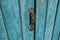 Old wooden door with handle, keyhole. Door with blue cracked paint.