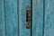 Old wooden door with handle, keyhole. Door with blue cracked paint.