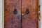 Old wooden door with intricate door handles and dorr knockers