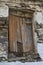 An old wooden door with lots of damage visible on the front of an abandoned house in Spain.