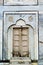 Old wooden door set in marble wall with designs