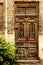 Old wooden door in yellow brick wall with plant