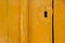 old wooden door in yellow. painted wood texture. metal overlay on the keyhole in the form of heart. background for your company