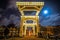 Old wooden Dutch bridge at night time against rush clouds.