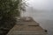 Old wooden fishing pier. Foggy morning on the lake