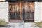 Old wooden garage doors with faded wooden boards and broken metal protection mounted on abandoned outdoor storage building