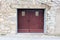 Old wooden garage doors made of wooden boards and rubber rain protection locked with rusted latch and padlock with two small