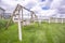 Old wooden garden swing on lush green grasses inside white picket fence