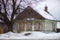 Old wooden green house with carved shutters in the country in Russiain winter under the tree