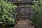 Old wooden grey hut in the village. Old time watermill among green trees in coutryside. Doors of ancient wooden building