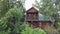 Old wooden house in greenery. Stock footage. Old residential cottage made of wood on background of green thickets. Old