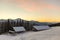 Old wooden house, hut and barn, pile of firewood in deep snow on mountain valley, spruce forest, woody hills on clear blue