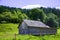 Old wooden house on the outskirts of the forest. Green grass