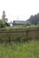 Old wooden house in the village abandoned in the grass with a fence