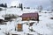 An old wooden house with a wooden gazebo stands on the side of a snowy mountain.