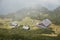 Old wooden houses in a scenic mountain valley in the fog. Tourist hiking shelter.