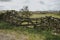 Old wooden hurdle between stone walls in a green meadow