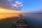 Old wooden jetty, pier reveals views of the beautiful lake, blue sky with cloud. Sunrise enlightens the horizon with orange warm