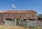 An old Wooden lean to barn with a rusty Tin roof, and the star of Texas hung on its wall.