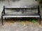 Old wooden park bench stands in front of a weathered stone wall.