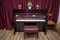 Old wooden piano keys on wooden musical instrument in front view . modern red piano bench . Big brown wooden piano and red bench