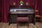 Old wooden piano keys on wooden musical instrument in front view . modern red piano bench . Big brown wooden piano and red bench