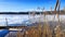 An old wooden pier on the shore of a lake with ice in early spring on a sunny day. Freezing lake in autumn and wooden