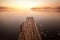 Old wooden pier on still lake with rising sun