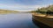 Old wooden rowing fishing boat moored near lake or river coast in beautiful autumn sunny day