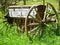 Old wooden and rusty iron barrow suspended in grass
