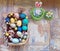 On the old wooden shabby table a dish with painted in different colors Easter eggs with feathers willow and chickens with rabbit