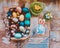 On the old wooden shabby table a dish with painted in different colors Easter eggs with feathers willow and chickens with rabbit
