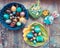 On the old wooden shabby table a dish with painted in different colors Easter eggs with feathers willow and chickens with rabbit