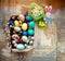 On the old wooden shabby table a dish with painted in different colors Easter eggs with feathers willow and chickens with rabbit