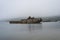 Old wooden shipwreck boat, foggy morning lonely shore. Abandoned antique old wooden ship