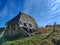 Old wooden stable house almost fallen with wooden roof top cover and holes from wind on sunny autumn day. Deserted and neglected