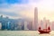 Old wooden tourist junk ferry boat in Victoria Harbor against famous Hong Kong island view with skyscrapers during sunrise