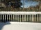 Old wooden village fence covered with snow. Snowy winter in the