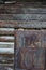 Old wooden wall with rusty metal door. Fragment of facade of a log house built at the end of 19th century in Russia