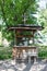 Old wooden well with a cross on the roof and bucket among the green grass in the village