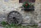 An old wooden wheel leaning against a stone wall