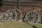 Old wooden wheels for wagon with metal rings near a wooden hut