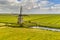 Old wooden windmill in green agricultural grassland