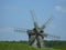 Old wooden windmills. Windmill with fresh green grass and clear blue sky on a summer day. Ethnic museum Pirogovo, Kyiv, Ukraine