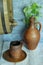 Old wooden wine barrel, ceramic jug and stein on wooden rustic table against dark concrete wall with ivy. Concept â€” rustic style