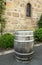 Old wooden wine barrel standing by stone wall of winery