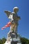 Old Worn Angel Statue With Tattered Flag and Blue Sky