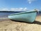 Old worn laminated blue fishing boat on lake bank. Close up view